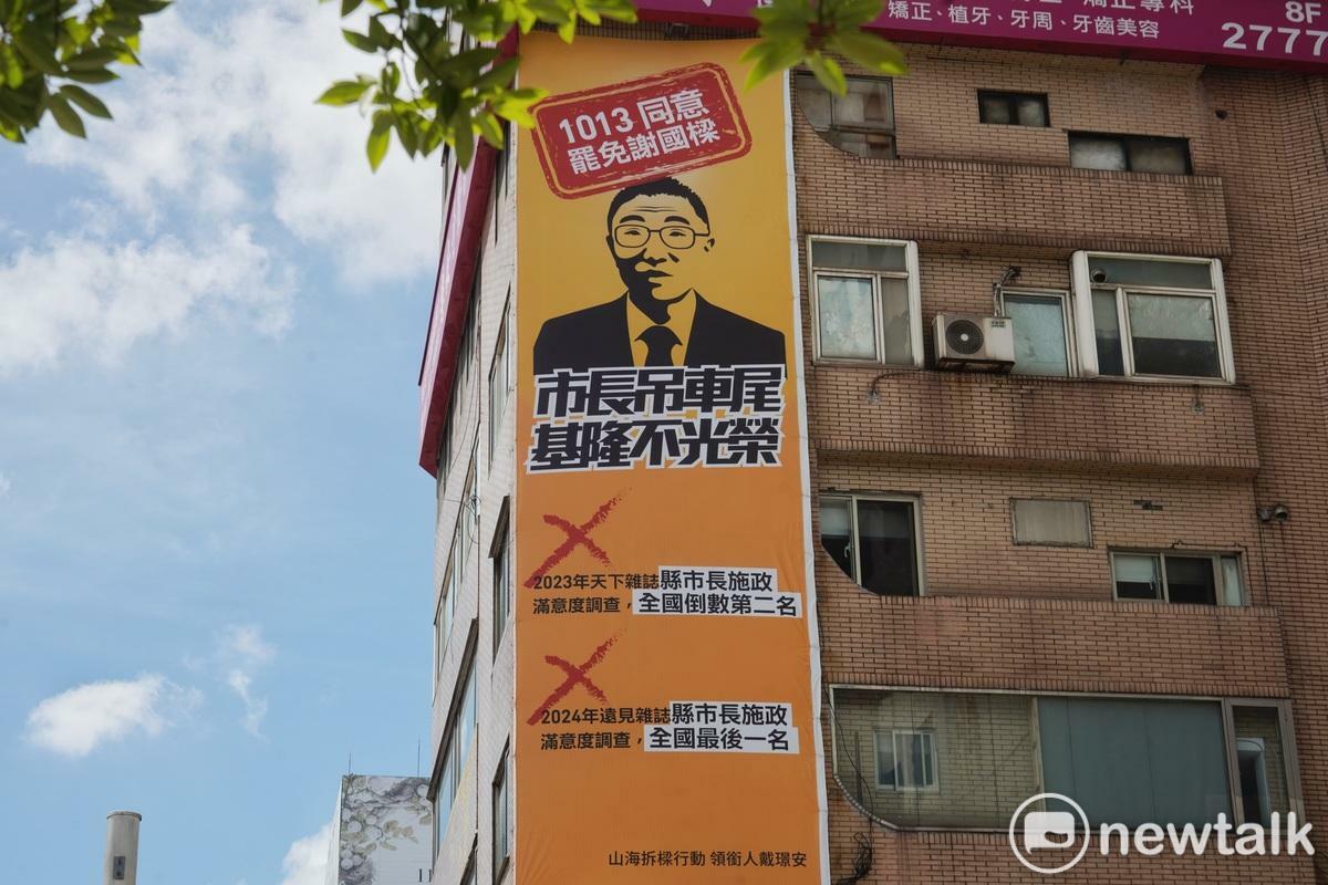 「山海公民拆樑行動」在台北忠孝東路四段一處大樓外牆掛上「謝國樑全台滿意度倒數」的大型看板。 圖：張良一攝 