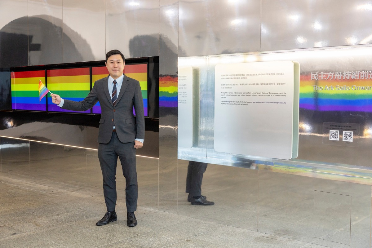  總統府明日將秀出彩虹旗挺同志遊行，圖為發言人李問與彩虹旗合照。 圖：翻攝自李問臉書 
