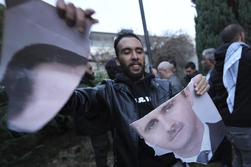  一位敘利亞民眾撕毀前總統阿薩德（Bashar al-Assad）的肖像，象徵這個國家一個強人時代的結束。 圖：達志影像／美聯社 