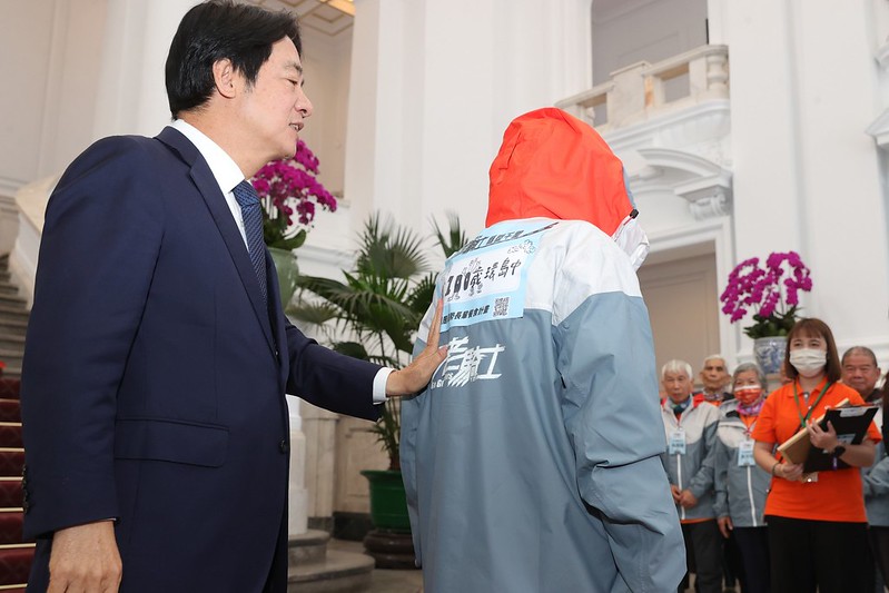  時任副總統賴清德昔日在郭深森衣服背面貼上「我100歲，環島中」大貼紙。 圖：總統府提供 