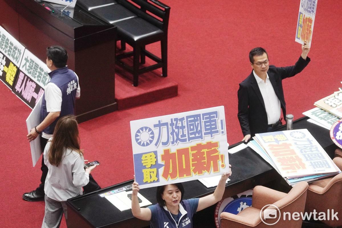 立法院長韓國瑜10日上午在院會敲槌三讀通過軍人待遇條例第五條，國民黨立委紛紛拿著力挺國軍加薪手舉牌在議場拍照。   圖：張良一/攝