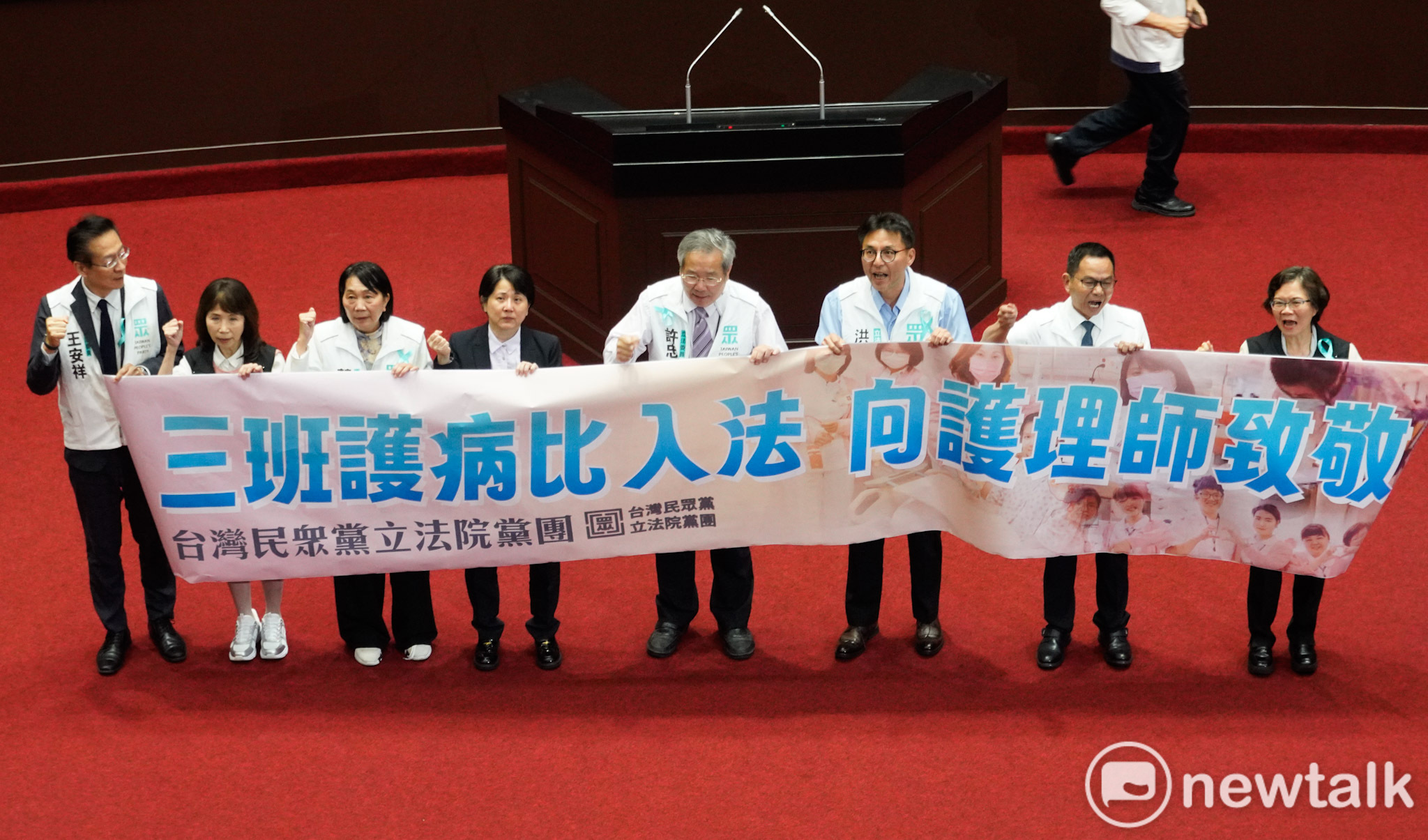  立法院三讀通過「醫療法部分條文修正草案」後，民眾黨立委在議場內舉牌支持「三班護病比」入法。 圖：張良一/攝 