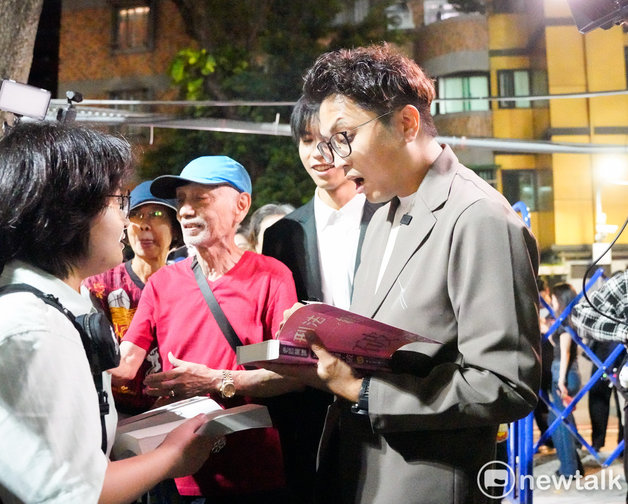  民進黨台北市長參選人沈伯洋出席「台北．無限之城」論壇前，一位學生拿著沈伯洋的著作請他簽名時，沈伯洋露出驚訝的表情。 圖：張良一/攝 