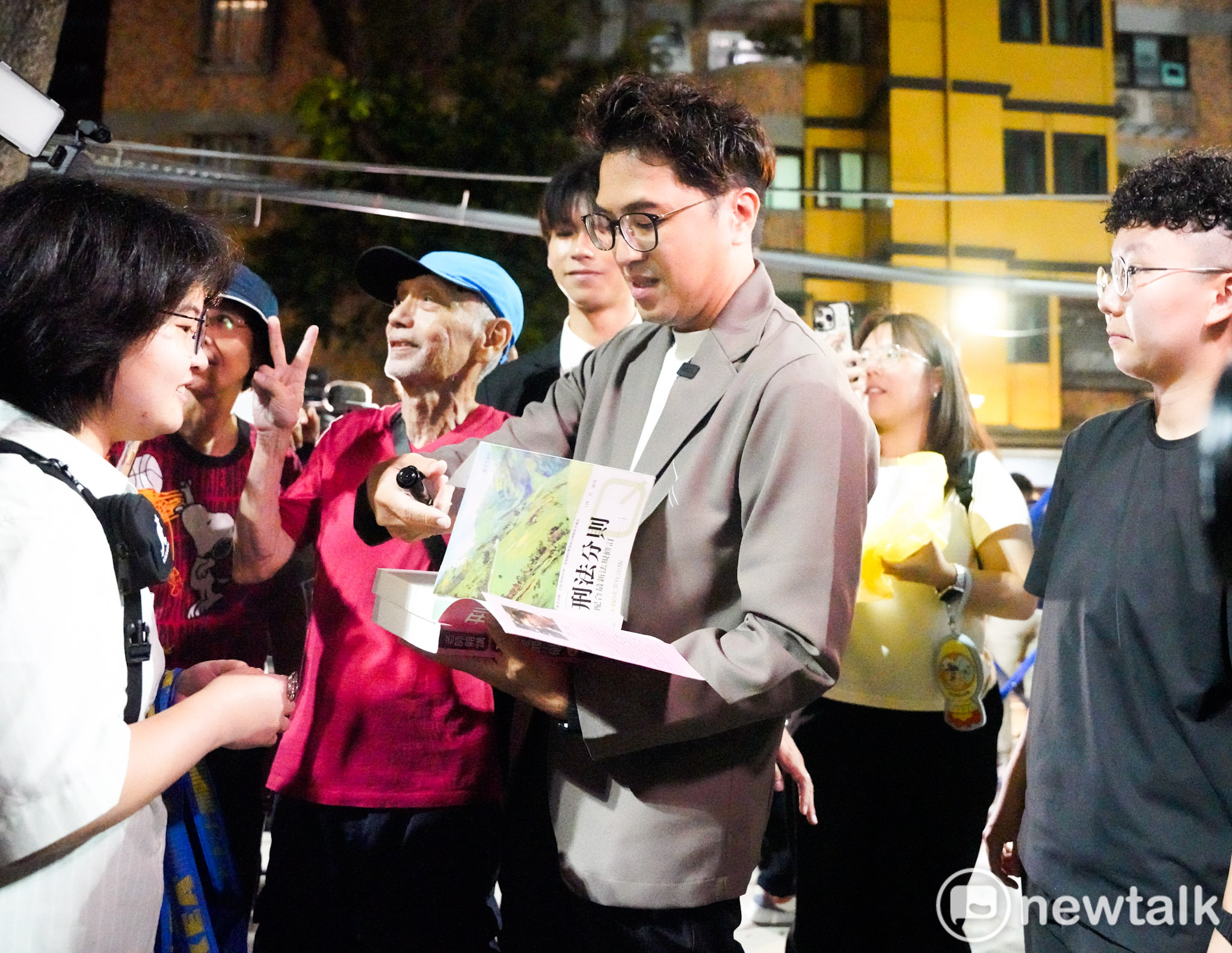  民進黨台北市長參選人沈伯洋出席「台北．無限之城」論壇前，一位學生拿著沈伯洋的著作請他簽名。 圖：張良一/攝 