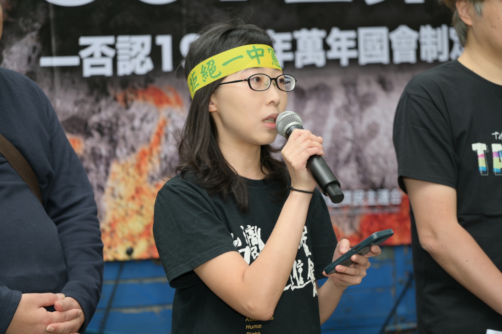  台灣人權促進會秘書長余宜家向前來參與遊行的群眾呼籲，一起否認由「萬年國代」所制定的憲法增修條文的效力，「而在未來的某一天，我們也要以台灣為名，制定一部真正屬於台灣人民的完整新憲法。」 圖：台灣經濟民主連合 提供 