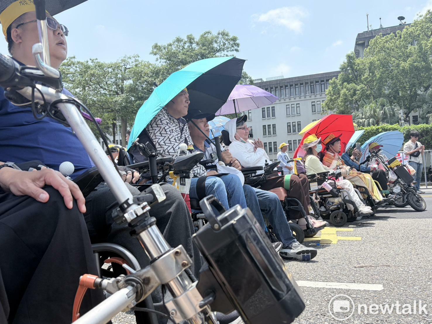  現場體感氣溫近30度，現場民眾撐傘阻擋日光曝曬。 圖：李宣萱/攝 