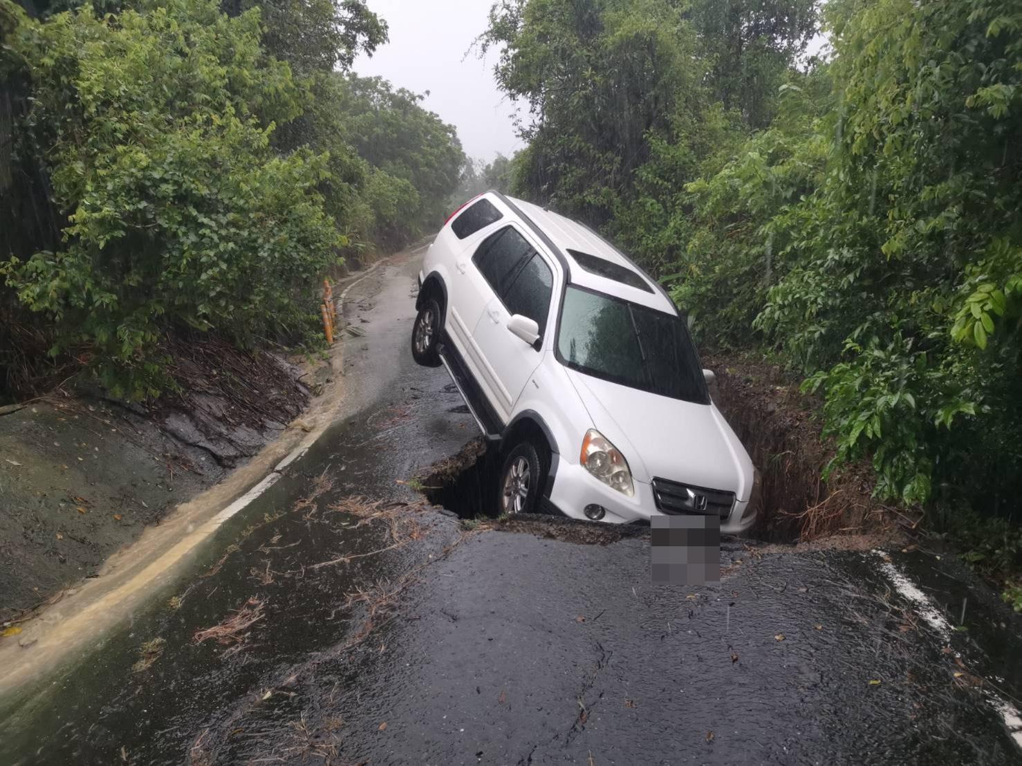  高雄市岡山區華崗里華崗路1巷3弄路段因豪雨出現天坑，一輛休旅車陷入其中。 圖：翻攝畫面 