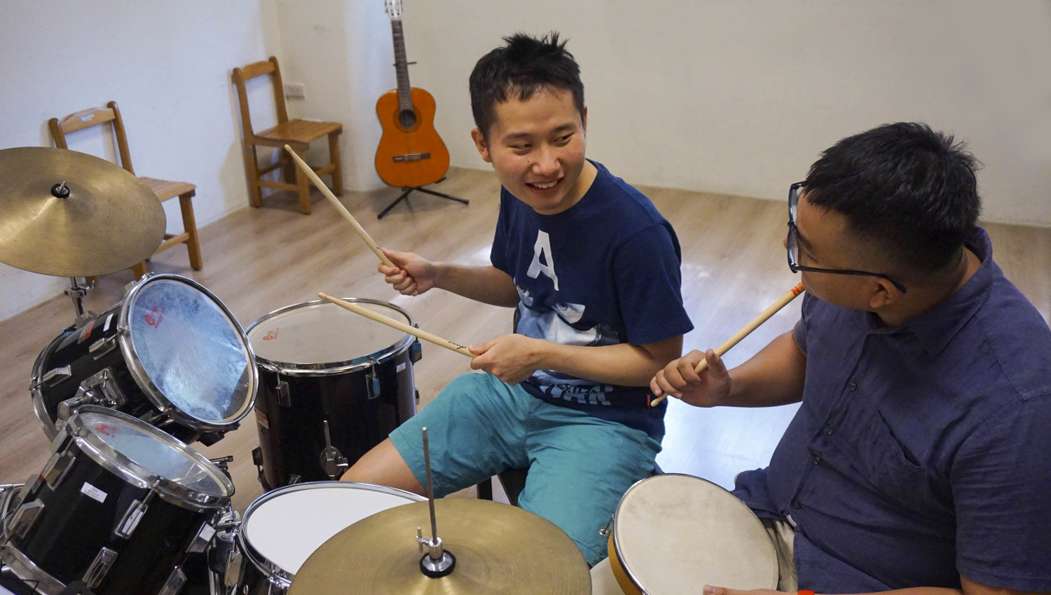 逢甲大學管樂團成員教導瑪利亞青年學習爵士鼓。
