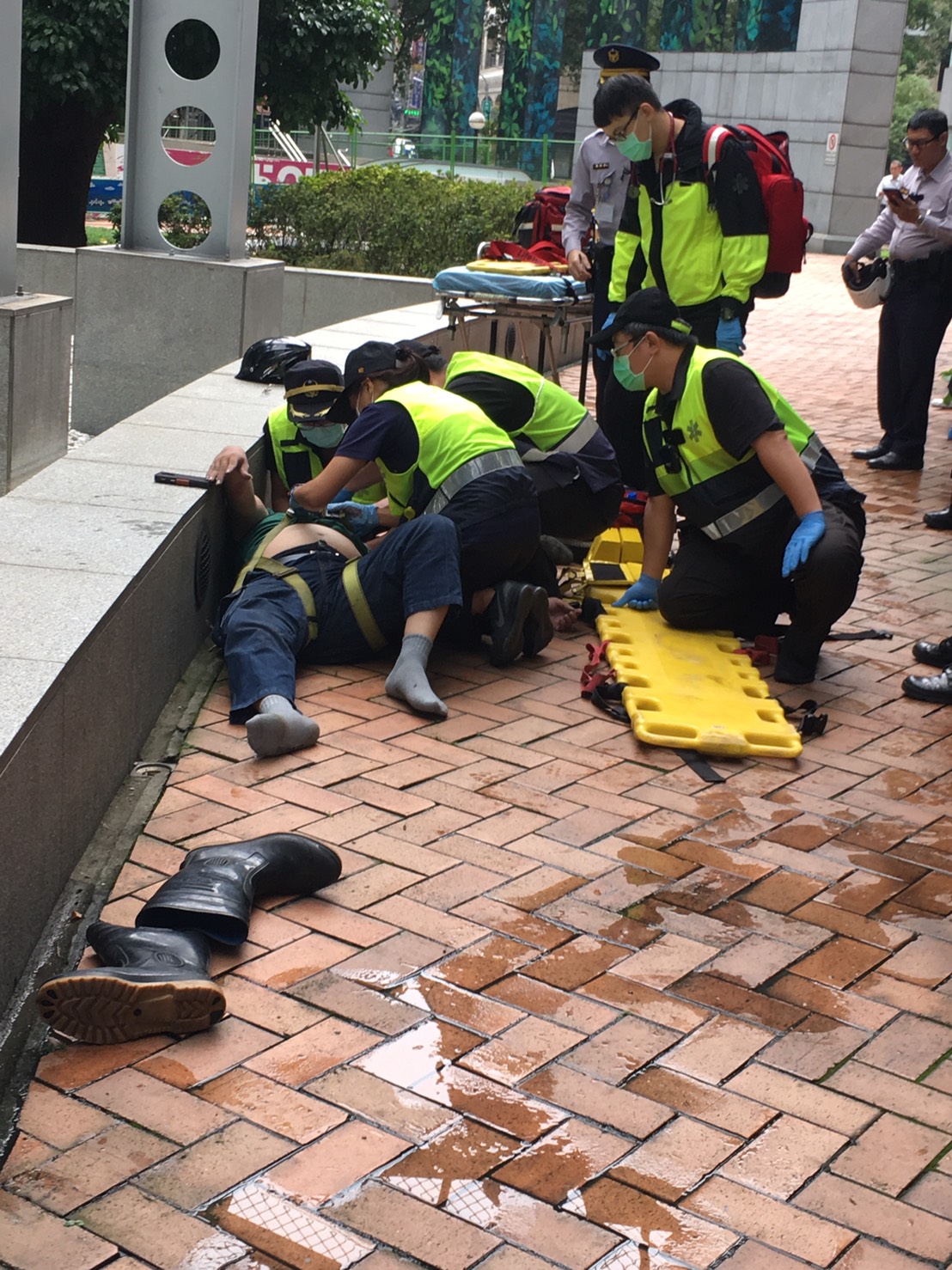 陳姓洗窗工人今早在新北市府工作時跌落地面，頭部血流，被緊急送醫。       
   圖：讀者提供      
