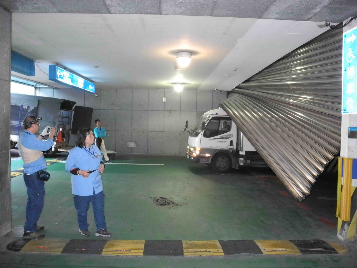 新北市府地下停車場B2到B1的西側入口處大型鐵捲門突然墜落，市府員工及機電人員在現場查看。    圖：王峻昌/攝