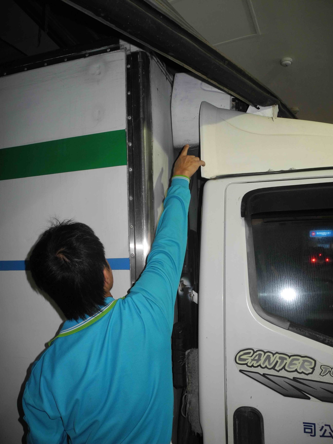 超商冷凍貨車的陳姓司機，心有餘悸地指著車頂被砸中的冷凍機。    圖：王峻昌/攝