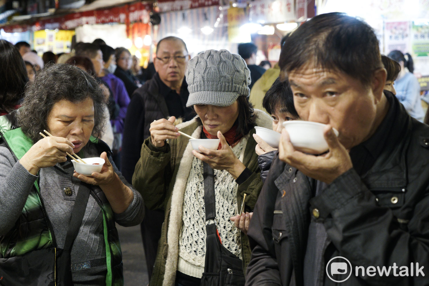 逛年貨大街的民眾試吃產品。   圖：張良一/攝