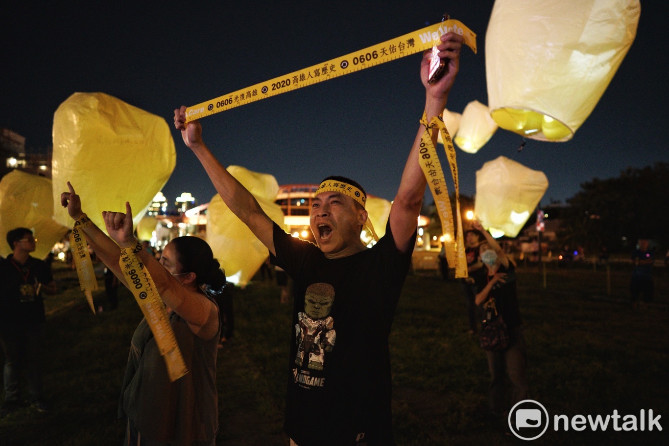 一位高雄市民在科技天燈旁高舉罷韓黃絲帶。   圖：張良一/攝