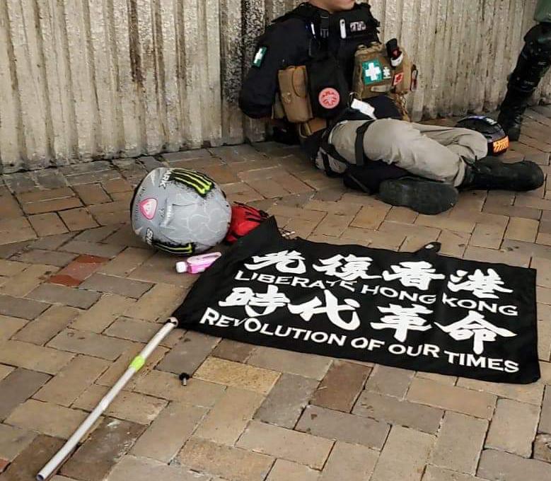 香港示威者坐在地上，前方有「光復香港，時代革命」旗幟。   圖：翻攝自香港警察臉書
