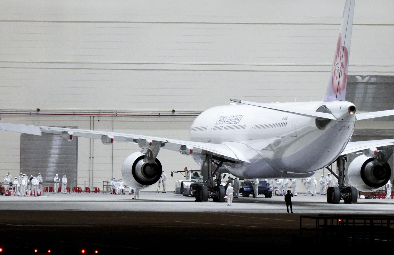 第二批武漢返台包機返抵桃園機場後,飛機被指引到維修機棚,由在場等候的檢疫人員為169位旅客、12位機組員及10位隨機醫護人員進行檢疫分組。圖:張良一/攝