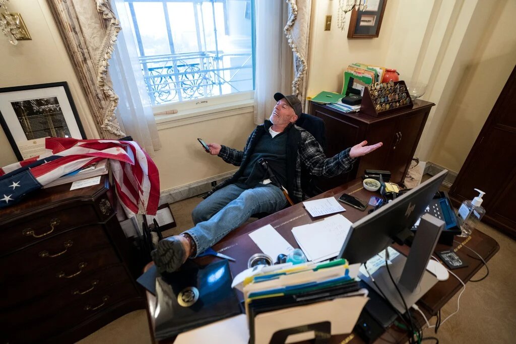川粉理查德·巴尼特（Richard Barnett）闖入眾議院議長佩洛西（Nancy Pelosi）的辦公室，不僅坐在裴洛西的椅子上，還大喇喇將腳翹在桌上。   圖：翻攝自推特