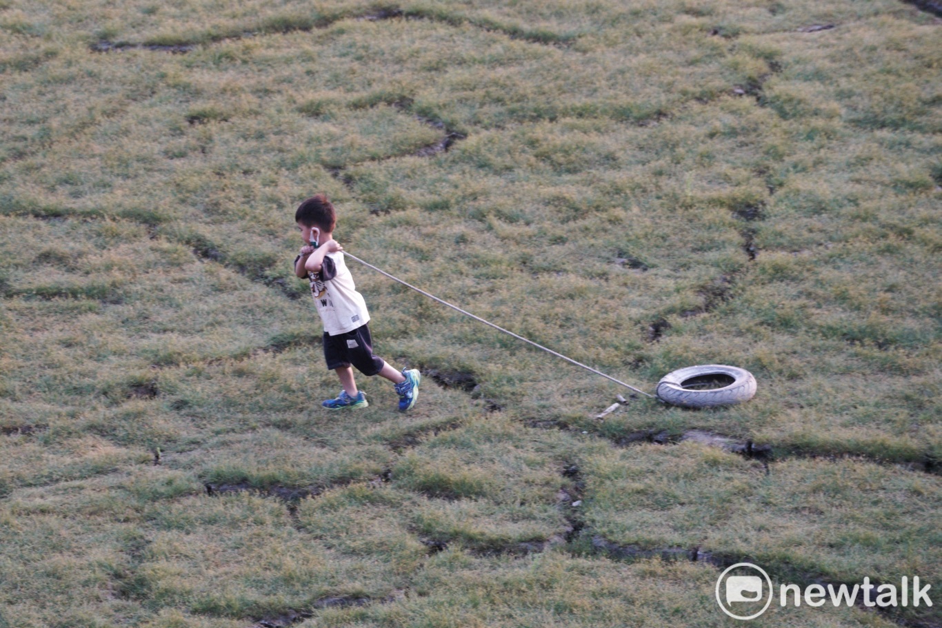 一位小朋友在日月潭大竹湖附近龜裂的湖底，拉著一條沉沒在湖底多年的廢棄輪胎。   圖：張良一/攝