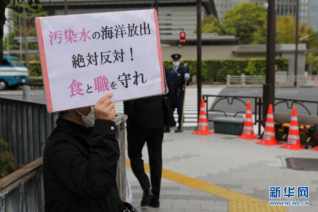 日本民眾舉牌反對核廢水入海。   圖：翻攝自新華社