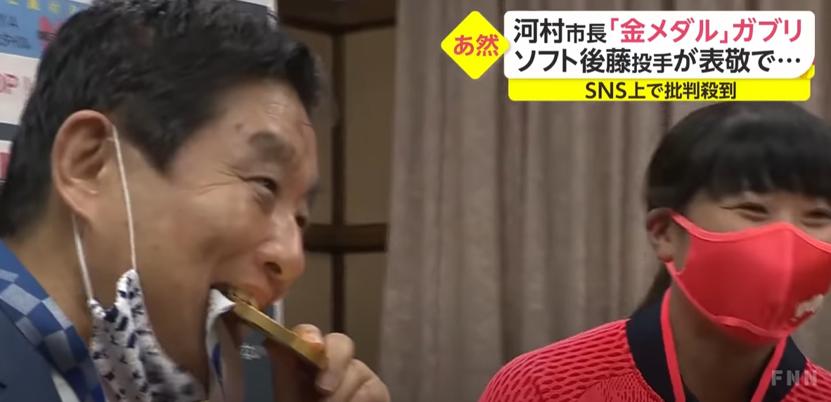 日本愛知縣名古屋市長河村隆在眾目睽睽下拉下口罩大口咬了後藤的金牌，挨批太過失禮。   圖：翻攝富士新聞網Youtube頻道