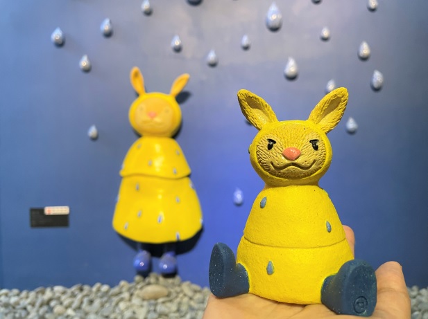 陳韋竹創作「雨天」裡穿著黃色雨衣的兔子，以純手工捏塑、彩繪的迷你版公仔，療癒性十足。   圖：鶯歌陶瓷博物館提供