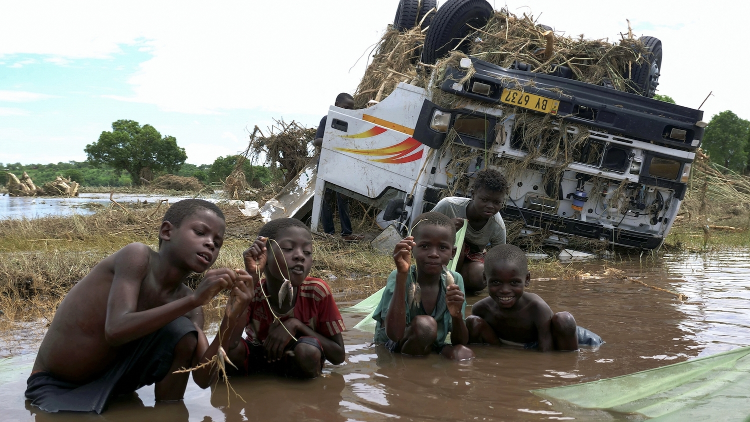 熱帶氣旋「安娜」侵襲馬拉威，當地塔布瓦村（Thabwa village）貨車殘骸旁，孩子們苦中作樂向記者分享漁獲。   圖：達志影像/路透社