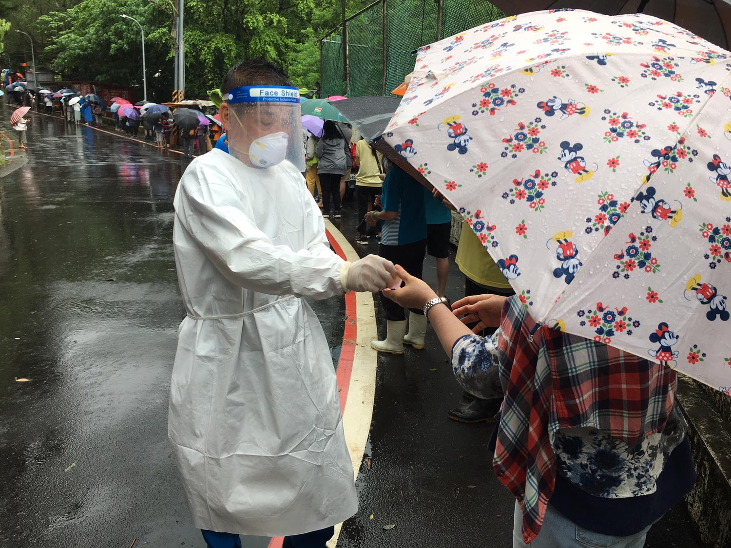許多民眾為了領取松山慈惠堂免費發放的快篩劑，冒雨排隊。   圖：網友授權提供