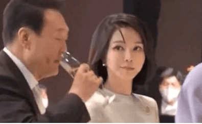 南韓總統尹錫悅正端著酒杯準備喝酒，一旁的總統夫人金建希立即轉頭，用十分銳利的眼神盯著尹錫悅。   圖 : 影片截圖