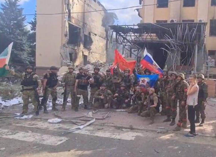 數名車臣士兵在利西昌斯克被摧毀的行政大樓前揮舞蘇聯國旗。   圖：翻攝自推特