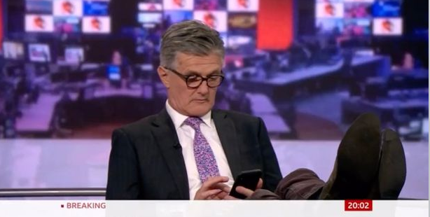BBC新聞主播蒂姆·威爾考克斯( Timothy Melton Willcox )被拍到在主播台翹腳、低頭滑手機。   圖 : 翻攝自推特