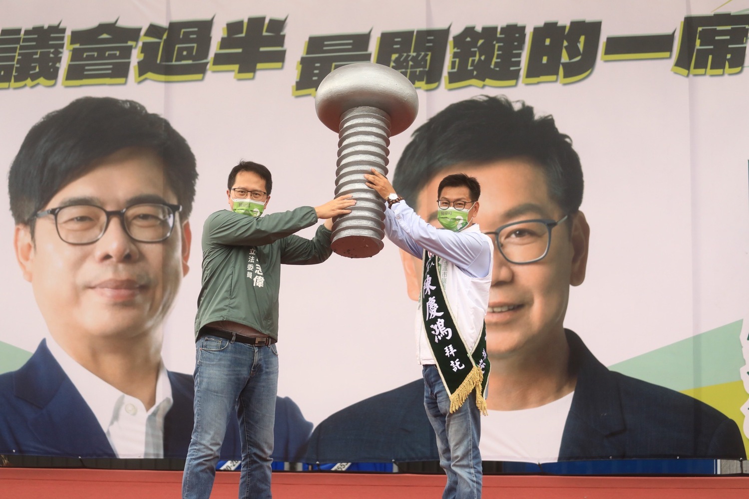 邱志偉(左)將一顆大螺絲交給陳慶鴻。.    圖：陳慶鴻提供