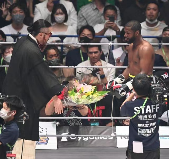 日本政客奧野卓志(左)當場將要獻給美國拳擊手梅威瑟(右)的花束摔在地上。   圖：翻攝自環球網