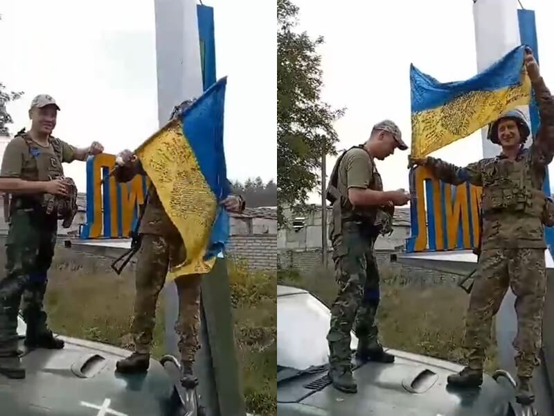 烏克蘭士兵在寫有利曼鎮名稱的標誌旁舉起烏克蘭國旗。   圖：翻攝推特