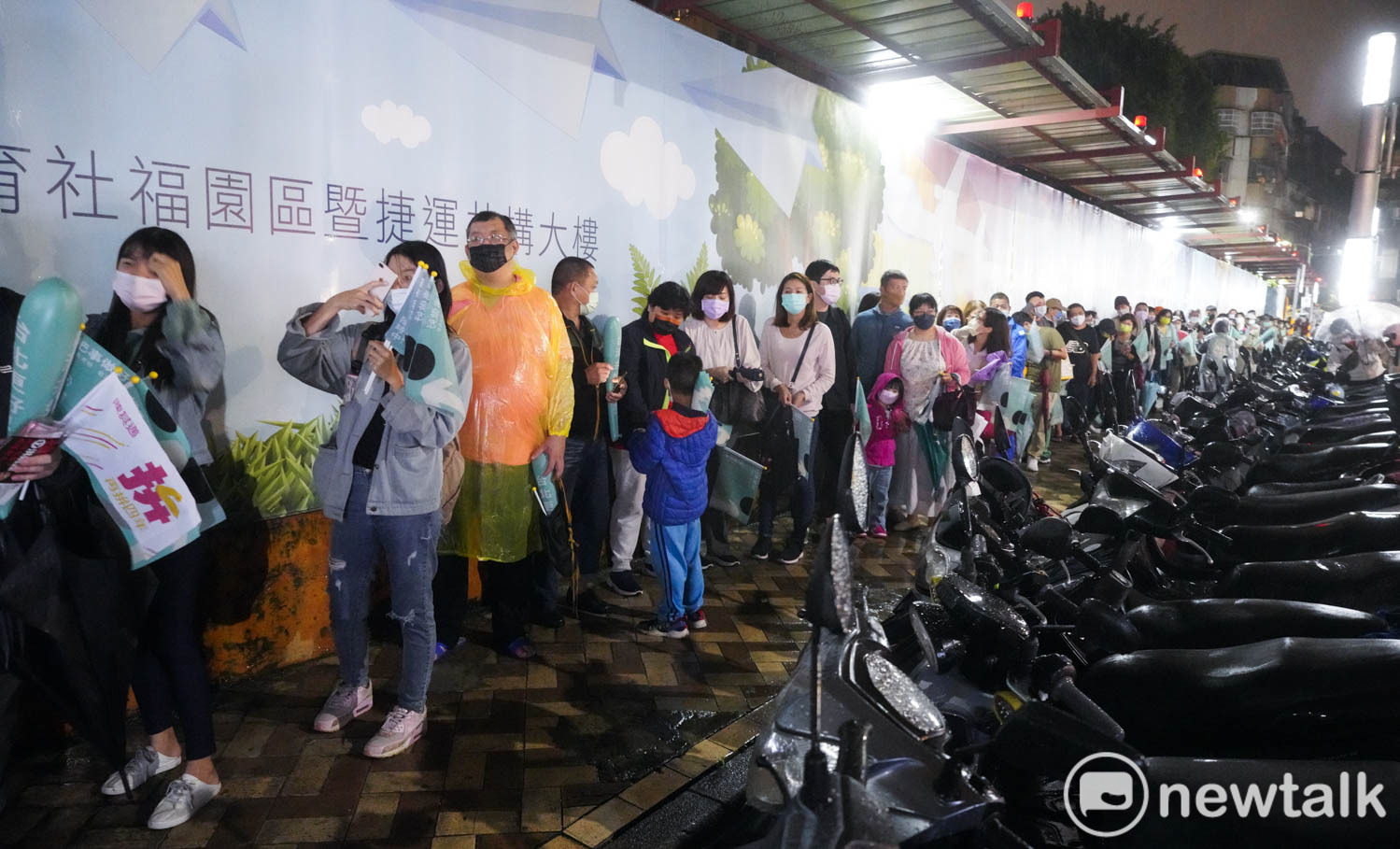 民進黨台北市長候選人陳時中今晚原訂到萬華南機場夜市掃街拜票，由於大雨，取消拜票行程，改到夜市外的人行道和支持者合影。晚間七點不到，排隊的支持者已經排到100公尺外。   圖：張良一/攝