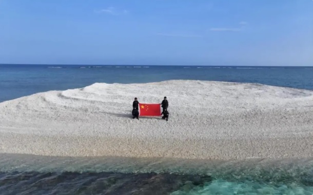  中國海警派遣人員前往鐵線礁高舉五星紅旗宣示主權。 圖：翻攝自 騰訊網 地球編輯 