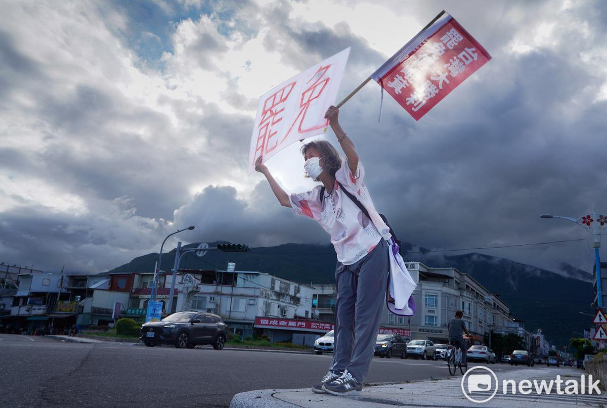  一位花蓮市民高舉「同意罷免」手舉牌，並彎腰向市民拜票。 圖：張良一/攝 